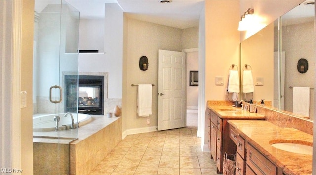 bathroom featuring a multi sided fireplace, vanity, tile patterned flooring, and tiled tub