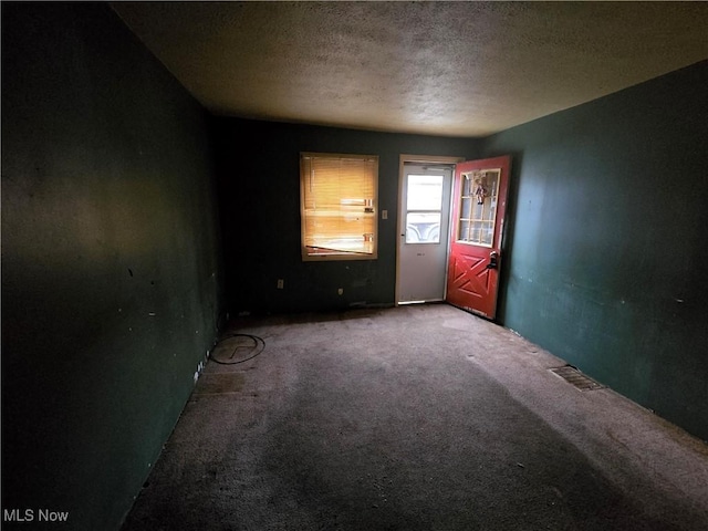 carpeted empty room featuring a textured ceiling