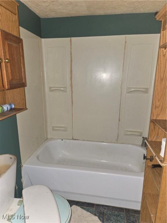 bathroom featuring toilet, shower / tub combination, and a textured ceiling