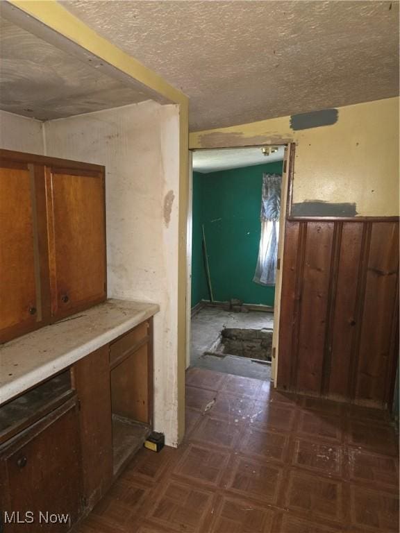 corridor featuring a textured ceiling and wooden walls