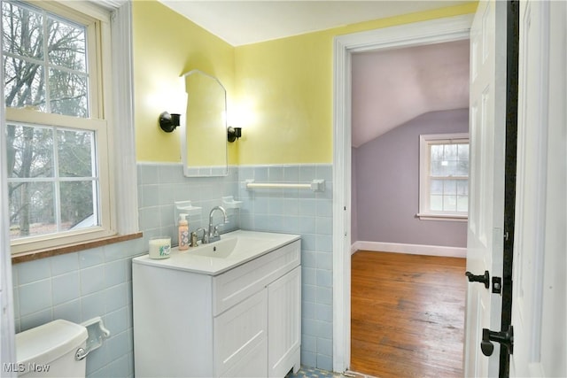 bathroom with vanity, vaulted ceiling, tile walls, hardwood / wood-style floors, and toilet