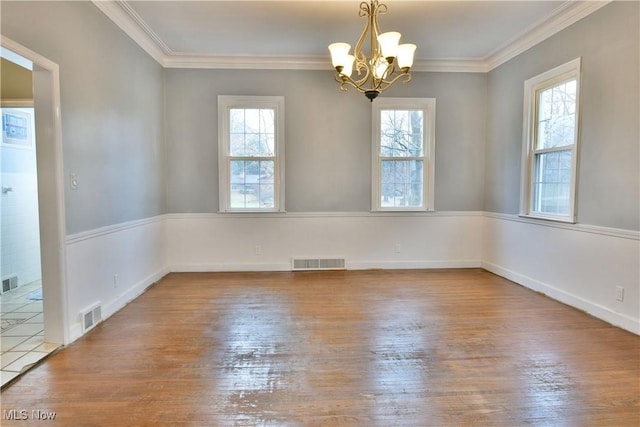 empty room featuring wood-type flooring, ornamental molding, and an inviting chandelier