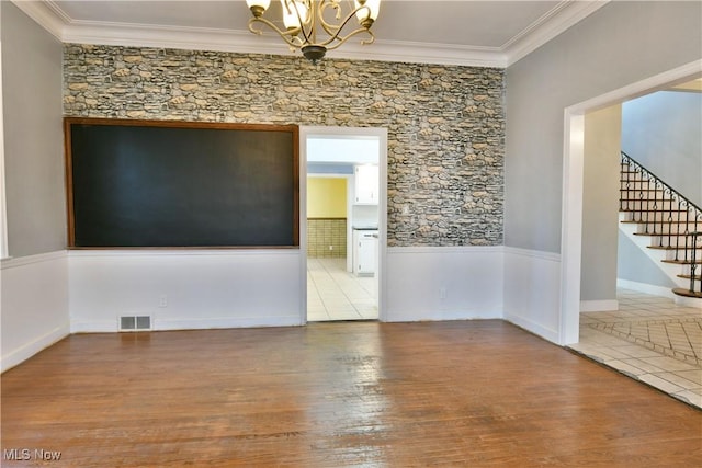 unfurnished room featuring light hardwood / wood-style floors, ornamental molding, and an inviting chandelier