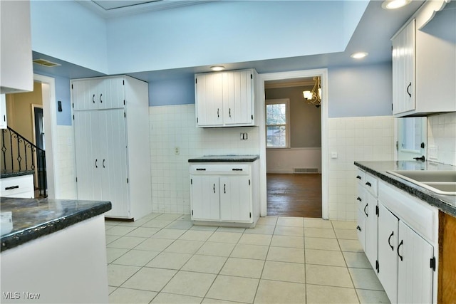 kitchen with a chandelier, sink, white cabinetry, and light tile patterned flooring