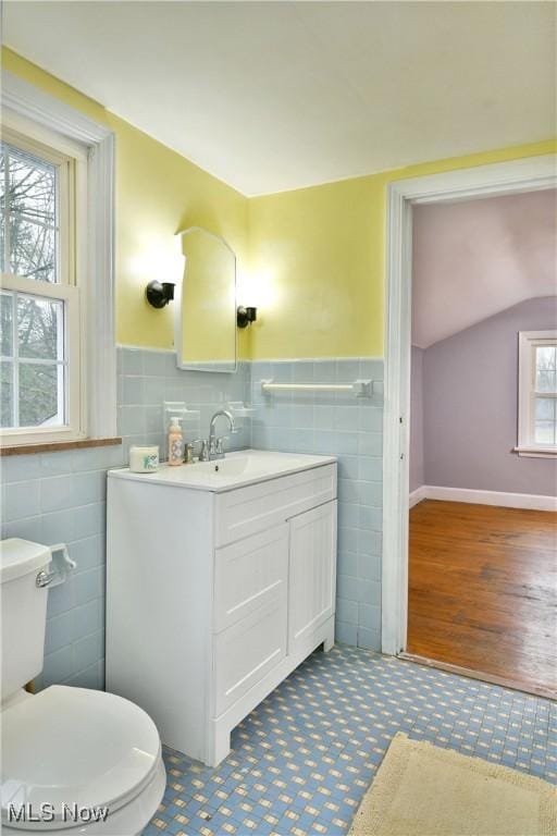 bathroom with vanity, toilet, and tile walls