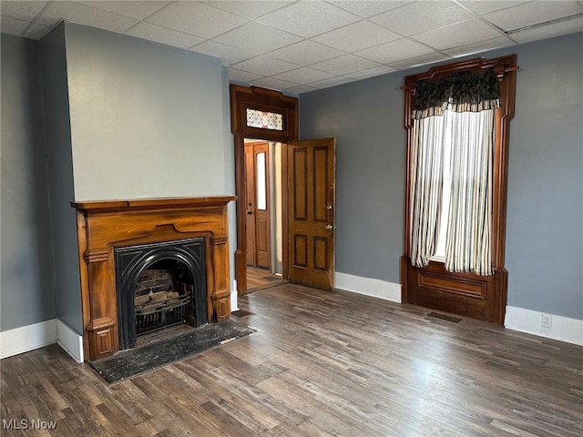 unfurnished living room featuring a drop ceiling and dark wood-type flooring