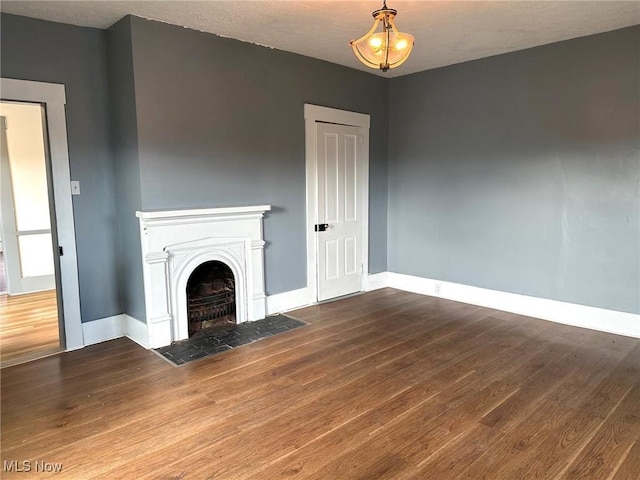 unfurnished living room with wood-type flooring and a notable chandelier