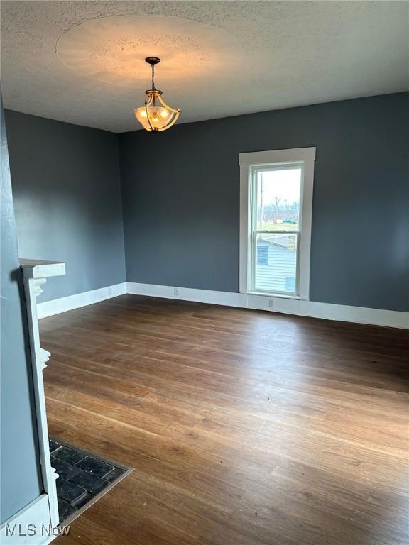 unfurnished room with a textured ceiling and dark wood-type flooring