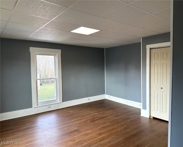 spare room with dark hardwood / wood-style floors and a drop ceiling