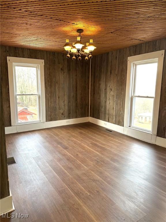 spare room featuring a chandelier, hardwood / wood-style floors, plenty of natural light, and wood ceiling