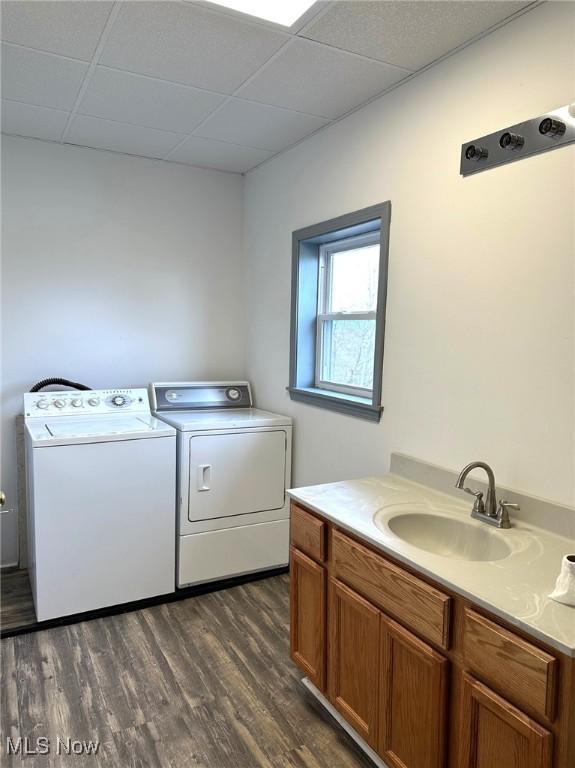 laundry room with washing machine and clothes dryer, dark hardwood / wood-style floors, and sink