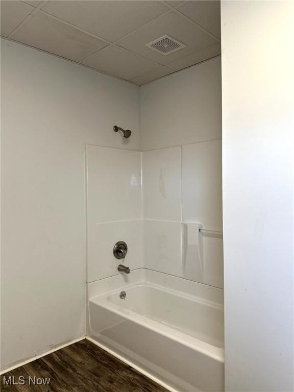 bathroom with hardwood / wood-style flooring, a drop ceiling, and washtub / shower combination