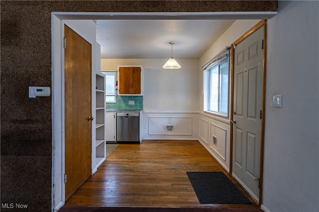 interior space featuring white cabinets, stainless steel dishwasher, hanging light fixtures, and light wood-type flooring