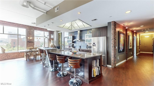 21 Furnace St Unit 705, Akron, OH 44308 - kitchen with stainless steel refrigerator with ice dispenser, wall chimney exhaust hood, brick wall, a breakfast bar area, and dark wood-style floors