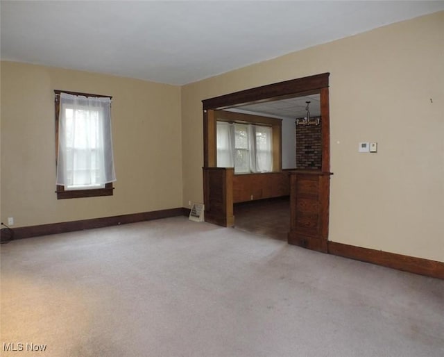 carpeted empty room featuring an inviting chandelier