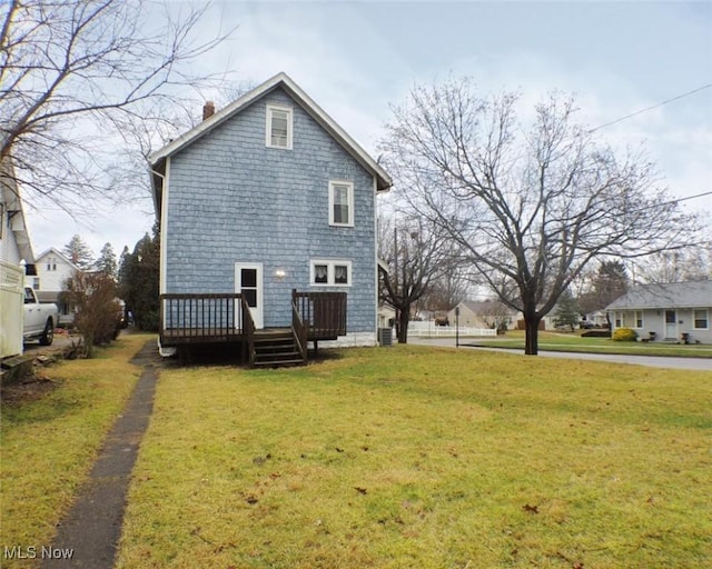 view of side of home with a wooden deck and a yard