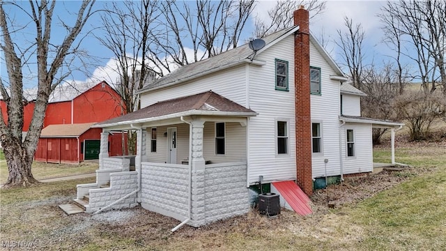 view of side of property featuring a yard, cooling unit, and covered porch