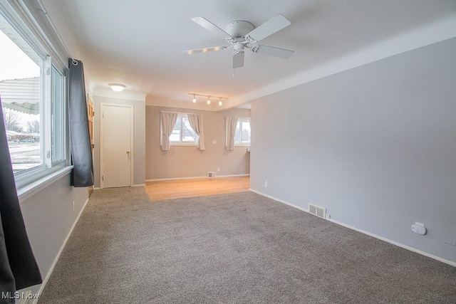 carpeted spare room with ceiling fan and track lighting