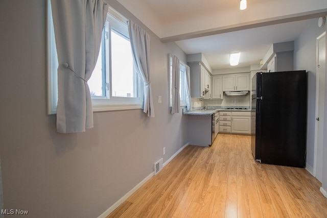 kitchen with tasteful backsplash, black appliances, and light wood-type flooring