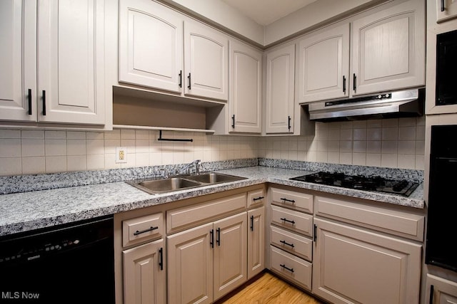 kitchen with black appliances, light wood-type flooring, sink, and tasteful backsplash