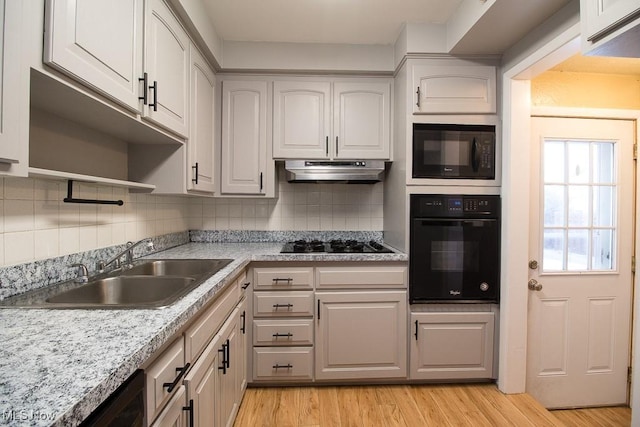 kitchen with light wood-type flooring, backsplash, sink, black appliances, and white cabinets