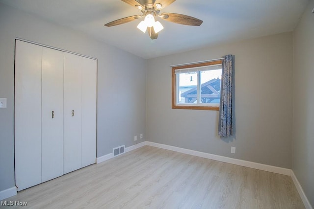 unfurnished bedroom with light wood-type flooring, a closet, and ceiling fan