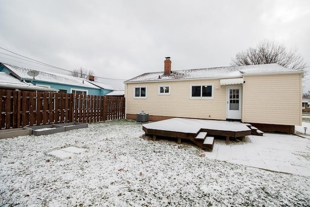 snow covered house with a wooden deck and cooling unit