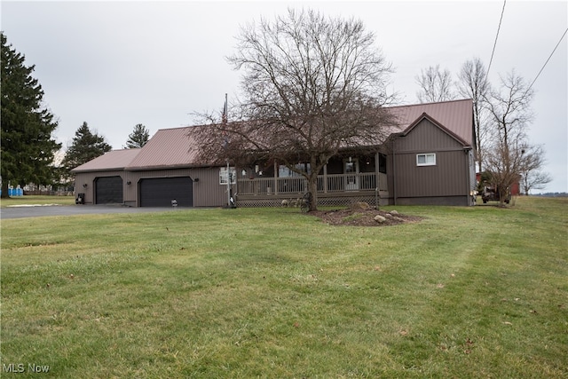 single story home featuring aphalt driveway, metal roof, an attached garage, and a front lawn