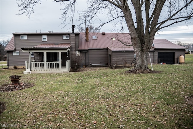 rear view of property featuring a yard, a garage, and covered porch