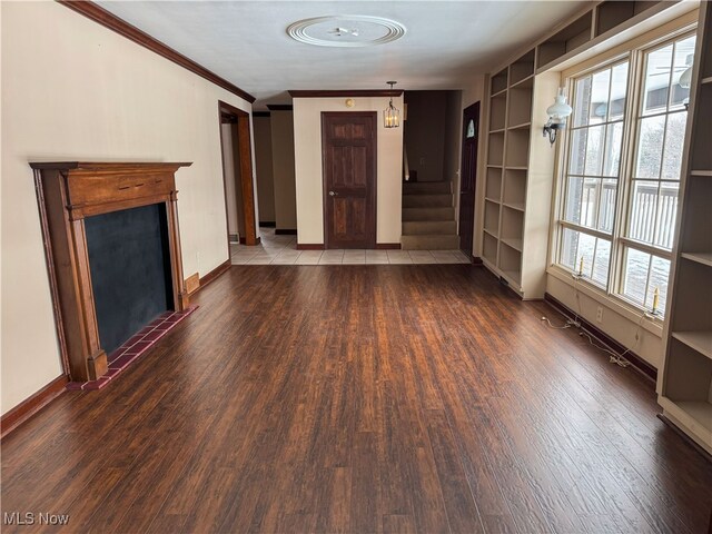 unfurnished living room with stairs, baseboards, ornamental molding, and wood finished floors