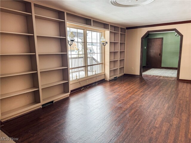 unfurnished room with arched walkways, baseboards, and dark wood-style floors