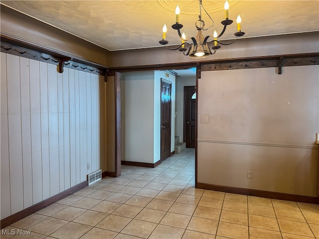 unfurnished dining area featuring a barn door, light tile patterned floors, a notable chandelier, and a textured ceiling