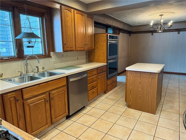 kitchen with a sink, appliances with stainless steel finishes, light tile patterned floors, and brown cabinets