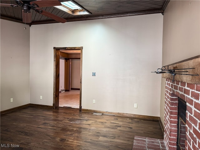 spare room featuring wood-type flooring, crown molding, a fireplace, and a skylight