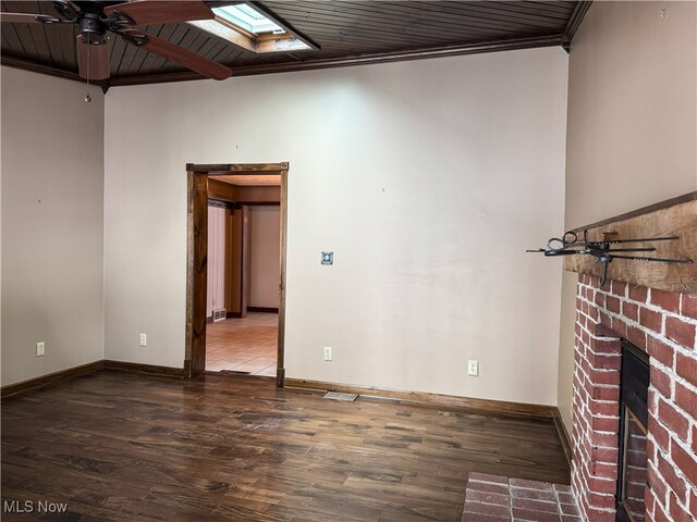 spare room featuring baseboards, a ceiling fan, wood finished floors, and a skylight
