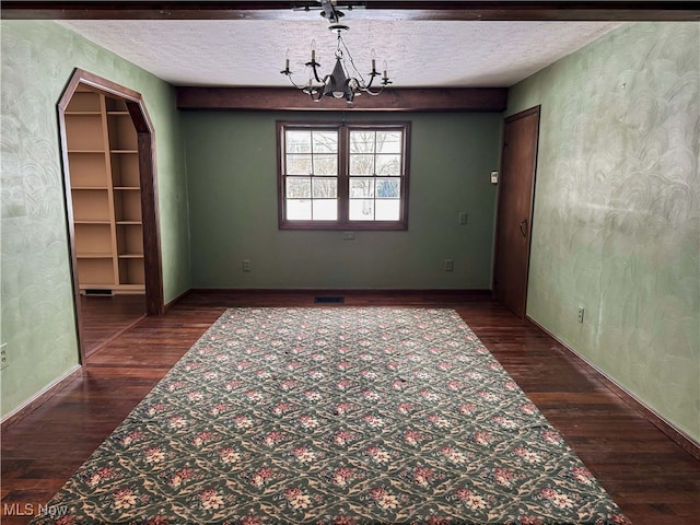 unfurnished dining area with dark wood-type flooring, a chandelier, and a textured ceiling