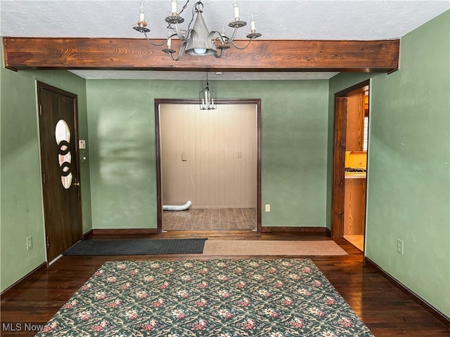 foyer with a textured ceiling, a chandelier, dark hardwood / wood-style floors, and beamed ceiling