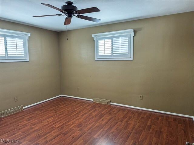 empty room with visible vents, a ceiling fan, baseboards, and wood finished floors