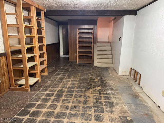 basement with a textured ceiling and wood walls