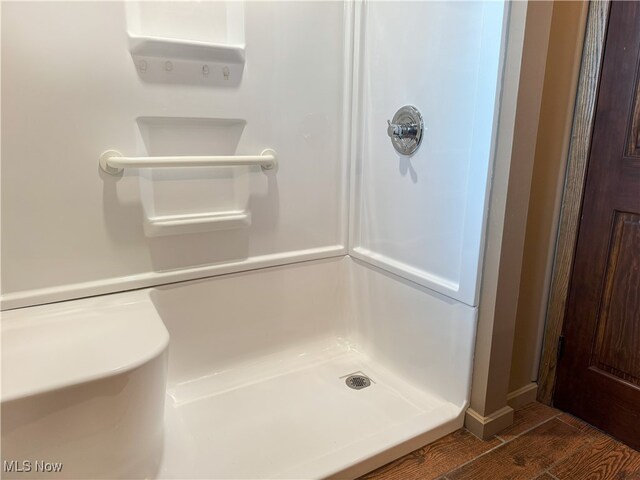 bathroom featuring wood finished floors and a stall shower