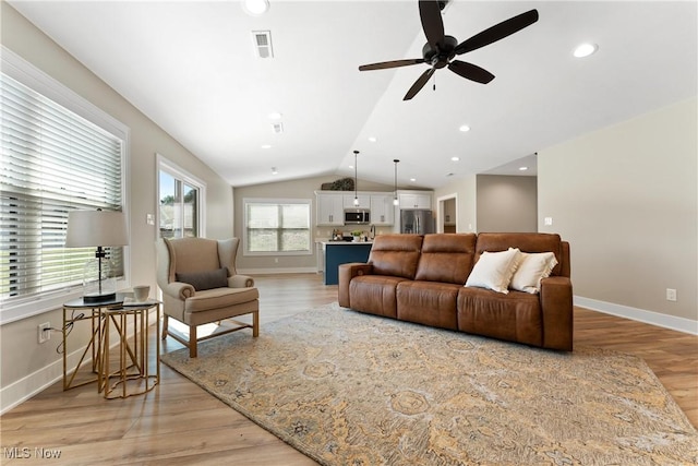 living room featuring ceiling fan, light hardwood / wood-style floors, and vaulted ceiling