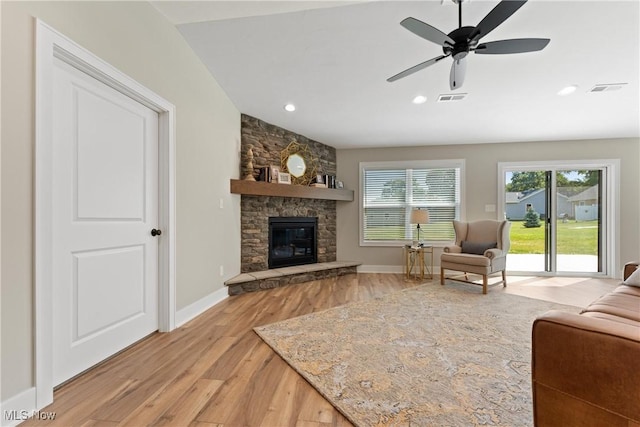 living room featuring ceiling fan, a fireplace, and light hardwood / wood-style flooring