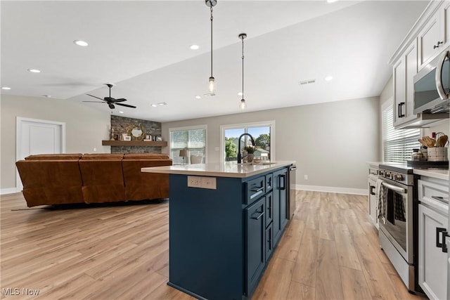 kitchen with a kitchen island with sink, white cabinets, blue cabinets, sink, and appliances with stainless steel finishes