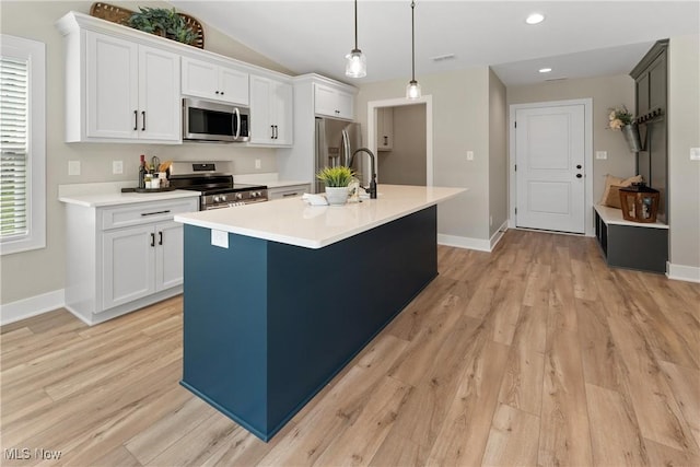 kitchen with white cabinets, a kitchen island with sink, stainless steel appliances, and hanging light fixtures