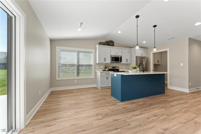 kitchen featuring white cabinetry, pendant lighting, lofted ceiling, a kitchen island with sink, and appliances with stainless steel finishes