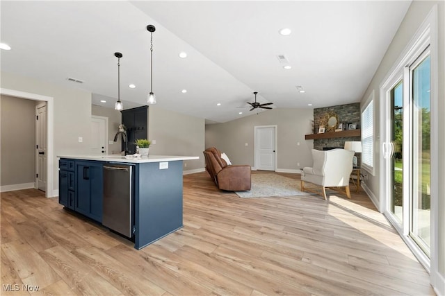 kitchen with ceiling fan, blue cabinetry, decorative light fixtures, light hardwood / wood-style floors, and an island with sink