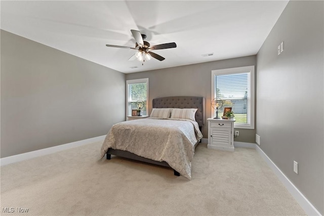 bedroom with ceiling fan, light colored carpet, and multiple windows