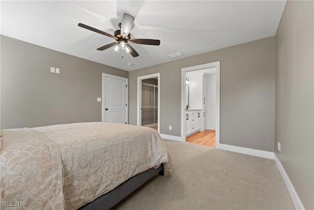 carpeted bedroom with ensuite bathroom, a spacious closet, a closet, and ceiling fan