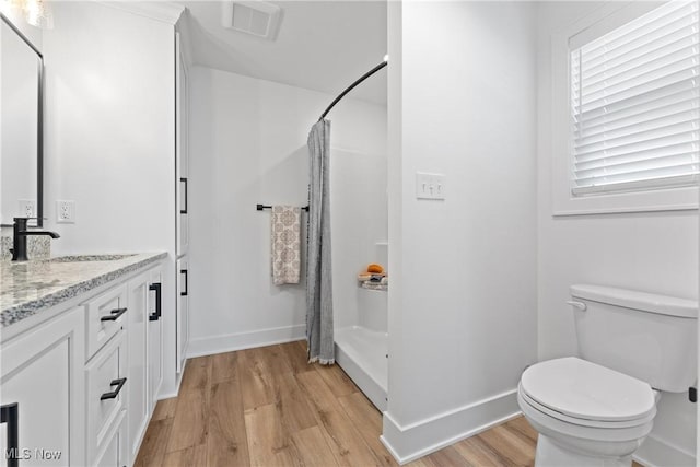 bathroom with vanity, hardwood / wood-style flooring, toilet, and walk in shower