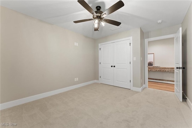 unfurnished bedroom with ceiling fan, light colored carpet, and a closet